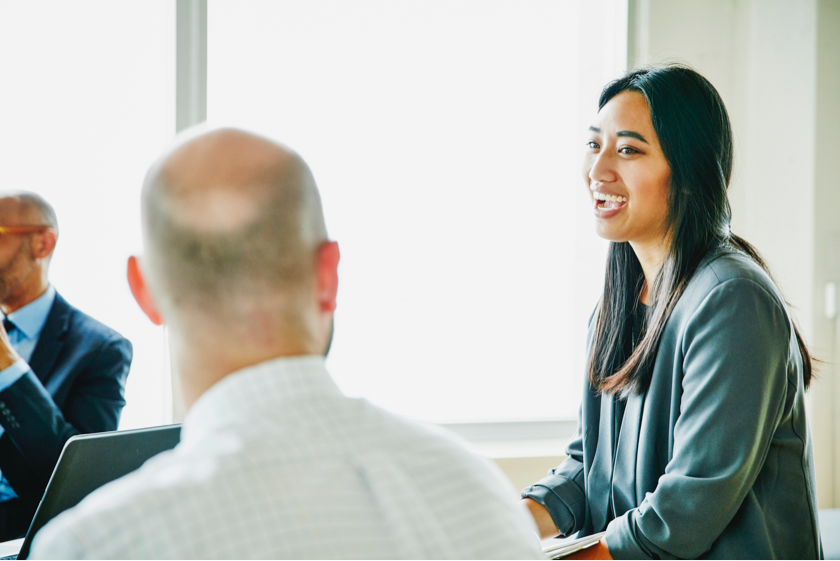 A woman speaking in a formal meeting setup.